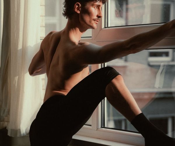 Man in his 60s performing a balancing yoga pose with a serene expression.